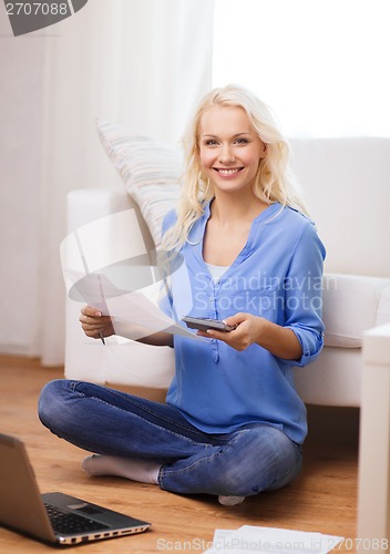 Image of smiling woman with papers, laptop and calculator