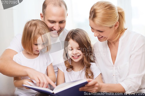 Image of smiling family and two little girls with book