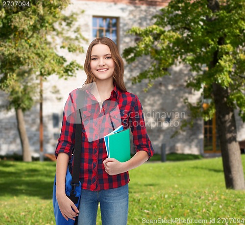 Image of smiling female student with bag and notebooks