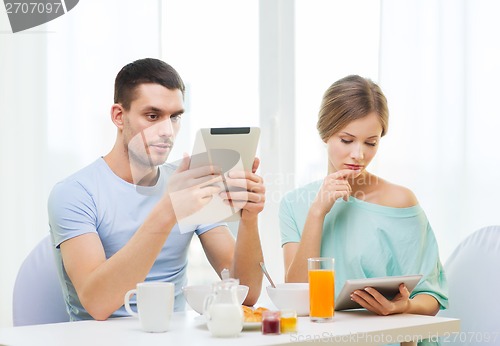 Image of concentrated couple with tablet pc reading news