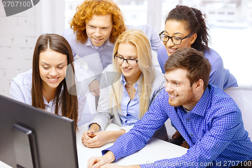 Image of smiling business team looking at computer monitor