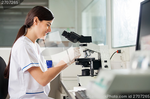 Image of Happy Female Scientist Using Microscope In Lab