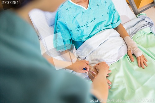 Image of Nurse Attaching IV Drip On Male Patient's Hand In Hospital