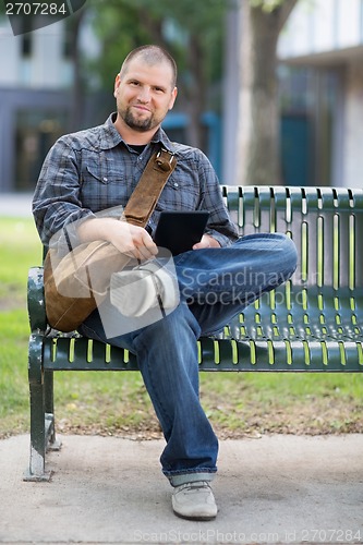 Image of Confident Male Student Sitting On Bench At Campus