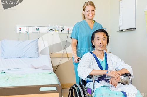 Image of Mature Patient Sitting On Wheelchair While Nurse Assisting Him