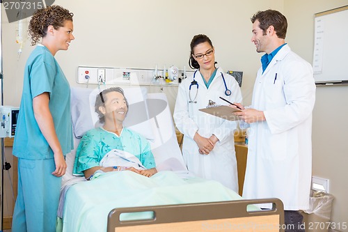 Image of Doctors Discussing Notes While Patient And Nurse Looking At Them