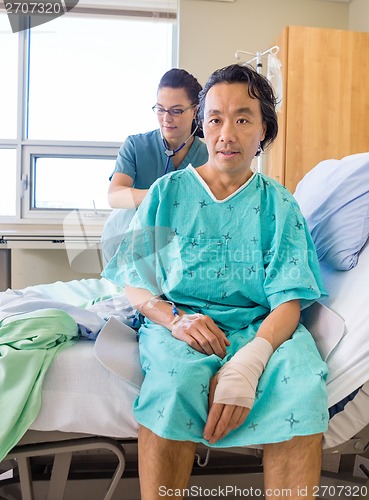 Image of Nurse Examining Patient's Back With Stethoscope On Hospital Bed