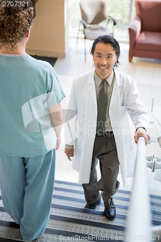 Image of Doctor Climbing While Nurse Walking Down Hospital Stairs