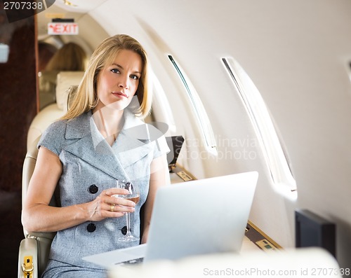 Image of Confident Businesswoman Holding Wineglass In Private Jet