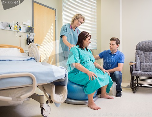 Image of Nurse And Man Assisting Pregnant Woman On Exercise Ball