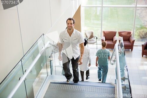 Image of Patient And Medical Team Walking On Stairs In Hospital