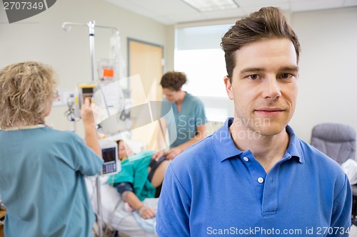 Image of Portrait of Man with Birthing Wife in Background