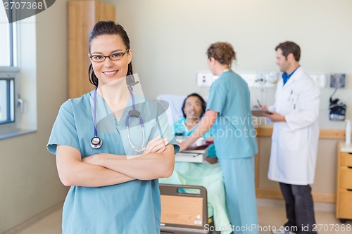 Image of Confident Nurse Against Patient And Medical Team At Hospital