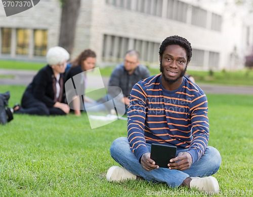 Image of Portrait Of Student Sitting On Grass At Campus Park