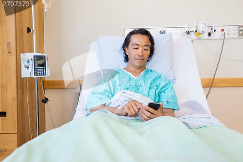 Image of Patient Text Messaging Through Cell Phone On Hospital Bed