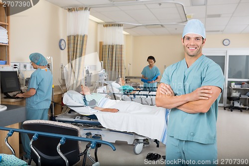 Image of Nurse With Colleagues And Patient's In Hospital Ward