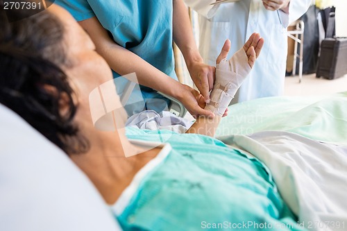 Image of Nurse Putting Bandage On Patient's Hand While Standing By Doctor