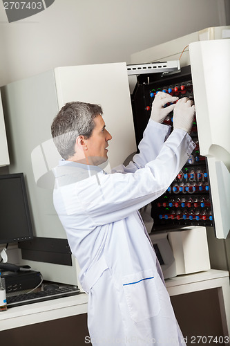 Image of Technician Placing Bottles Into Blood Culture Instrument