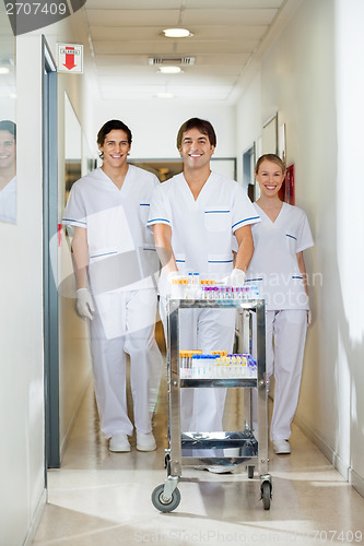 Image of Technicians With Medical Cart Walking In Corridor