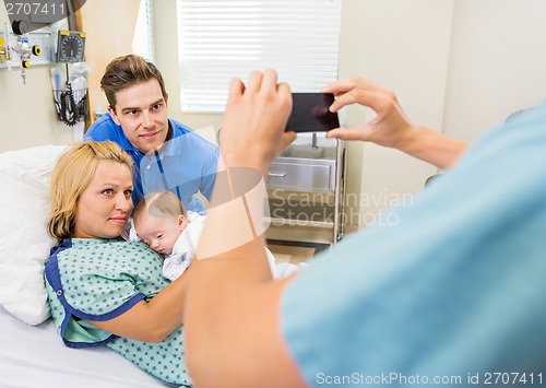 Image of Nurse Photographing Couple With Newborn Baby Through Mobilephone