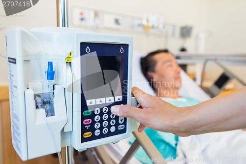Image of Nurse Operating IV Machine While Patient Lying On Bed