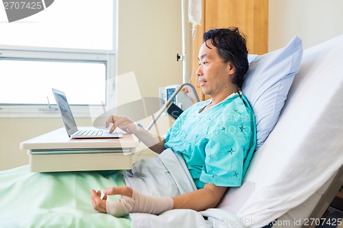 Image of Patient With Crepe Bandage On Hand Using Laptop