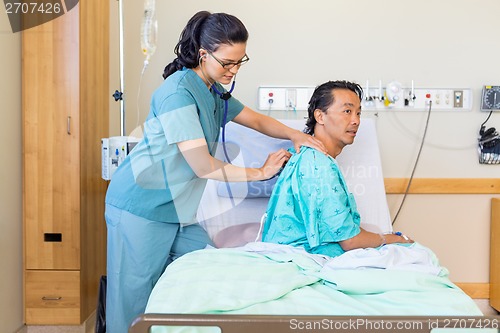 Image of Nurse Examining Male Patient's Back With Stethoscope On Hospital