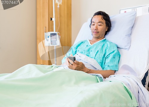 Image of Patient Using Mobile Phone On Hospital Bed