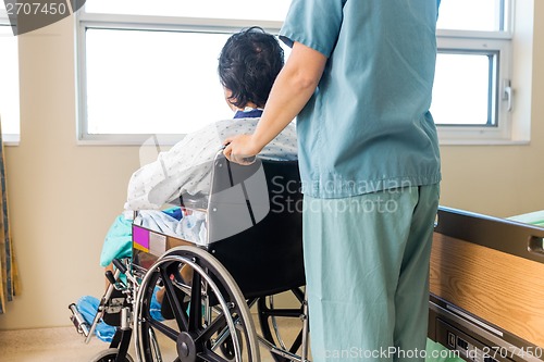 Image of Nurse Holding Patient's Wheelchair's Handle By Window