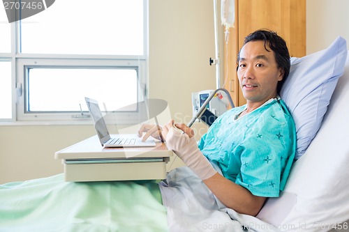 Image of Patient With Crepe Bandage On Hand Using Laptop On Bed