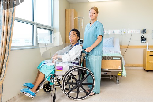 Image of Patient On Wheel Chair While Nurse Standing Behind At Window