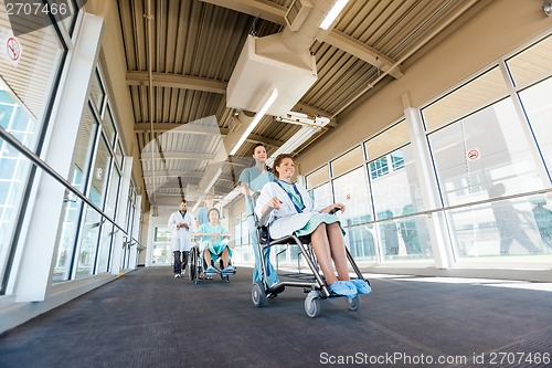 Image of Nurses Pushing Patients On Wheelchairs At Hospital Corridor