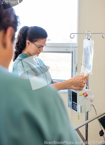 Image of Nurse Adjusting IV Bag With Coworker In Foreground