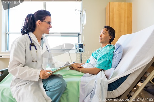 Image of Doctor Consoling Male Patient Relaxing On Hospital Bed