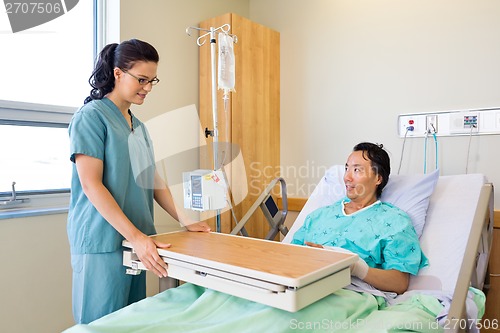 Image of Nurse Placing Overbed Table For Male Patient