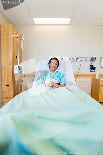 Image of Patient Messaging Through Mobile Phone On Hospital Bed