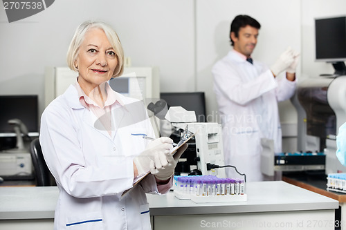 Image of Female Scientist Writing On Clipboard In Laboratory