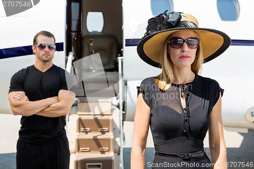 Image of Beautiful Woman With Bodyguard Against Private Jet