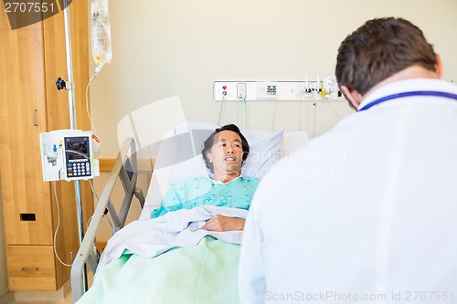 Image of Male Patient Looking At Doctor While Lying On Hospital Bed