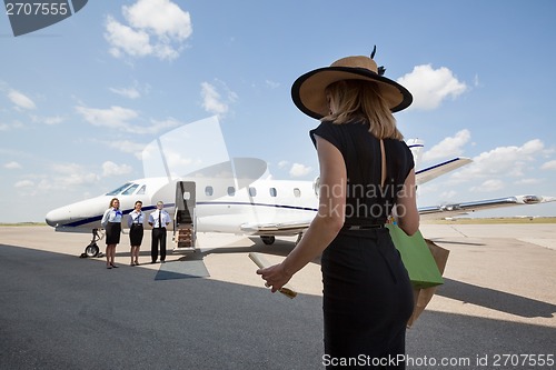 Image of Woman Walking Towards Pilot And Stewardesses Against Private Jet