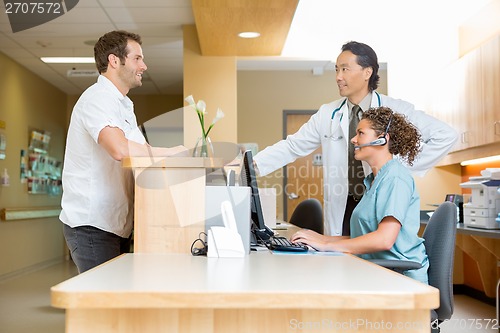 Image of Patient With Doctor And Nurse At Reception Desk