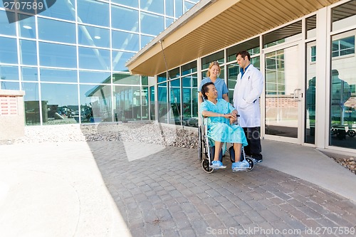 Image of Nurse And Doctor Looking At Patient On Wheelchair At Courtyard