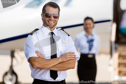 Image of Confident Pilot Against Stewardess And Private Jet