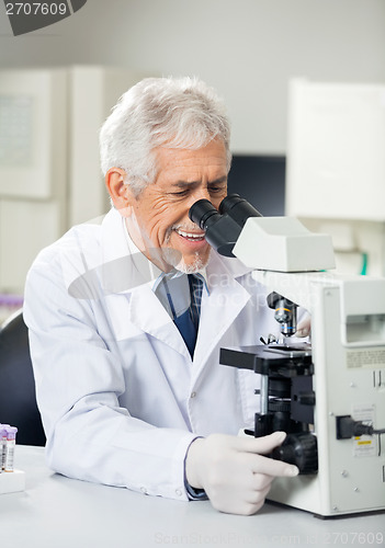 Image of Smiling Scientist Using Microscope In Laboratory