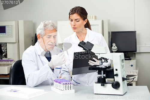 Image of Scientist Reading Sample While Colleague Taking Notes