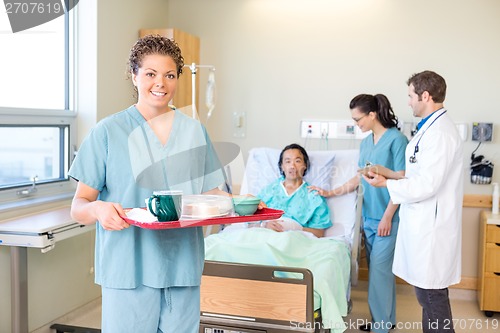 Image of Nurse Holding Tray With Medical Team And Patient In Background