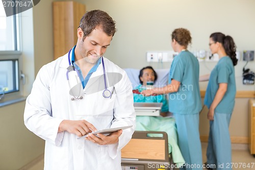 Image of Doctor Using Digital Tablet While Nurses Serving Breakfast To Pa