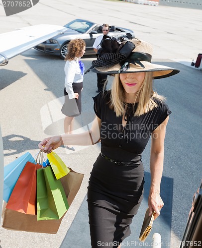 Image of Rich Woman Carrying Shopping Bags While Boarding Private Jet