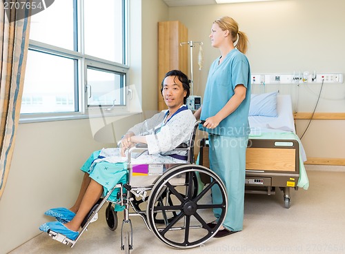 Image of Patient On Wheel Chair With Nurse Standing Behind At Window