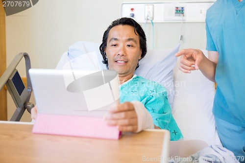 Image of Nurse Pointing At Digital Tablet While Patient Using It